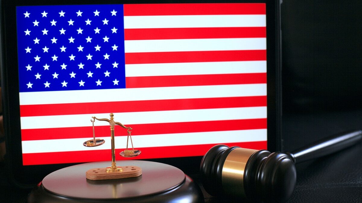 A gavel and a scale of justice in front of the American flag