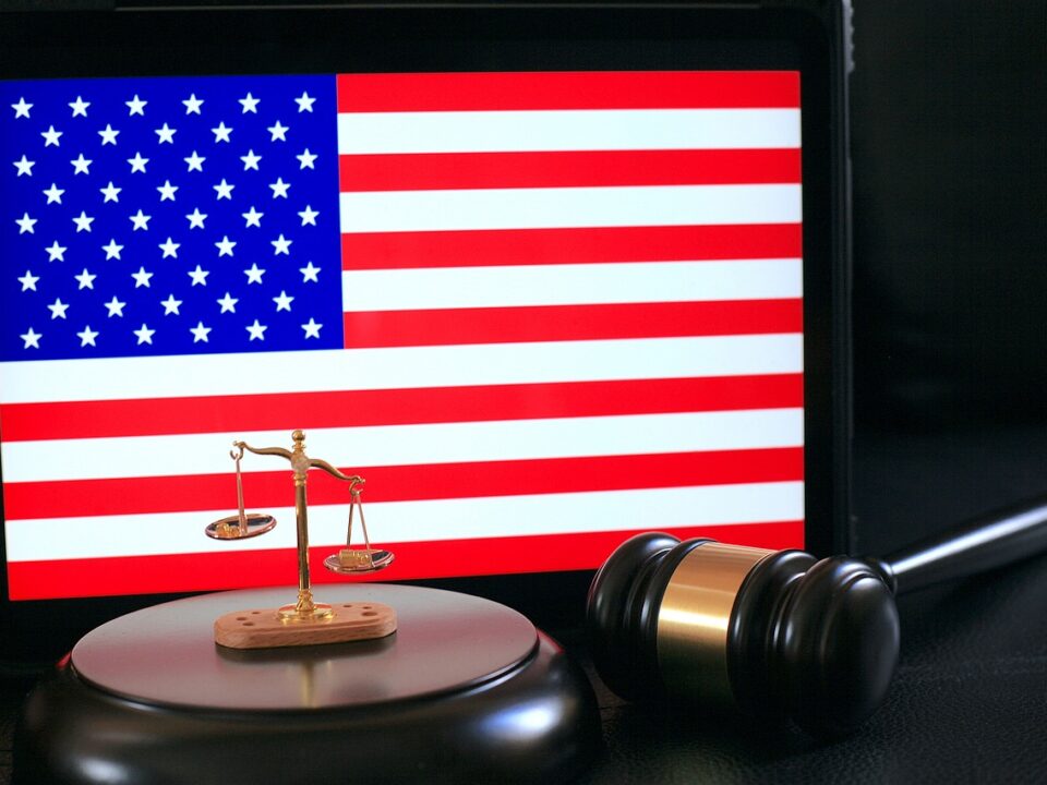 A gavel and a scale of justice in front of the American flag