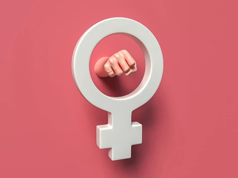 female gender symbol in white in the midlle of a pink background, a fist of a woman's hand through the circle of the symbol