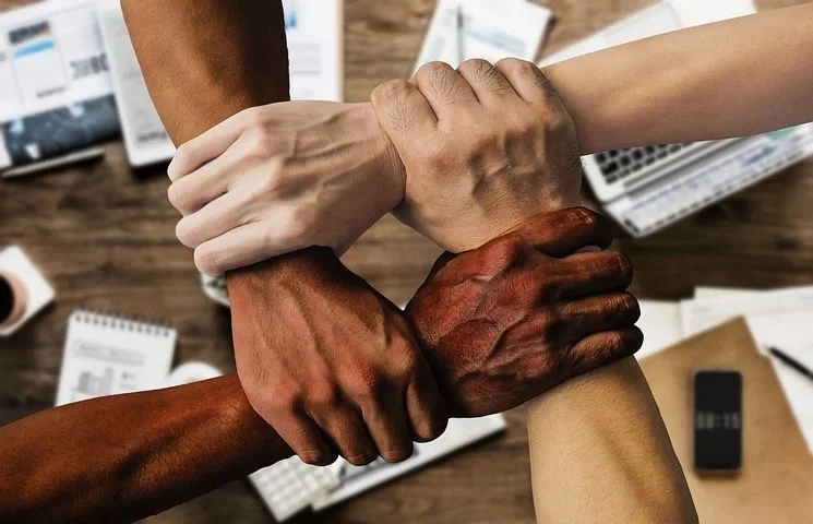 arms of different colours in a workplace hanging from each other